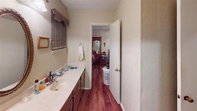 bathroom with wood-type flooring, vanity, and a textured ceiling