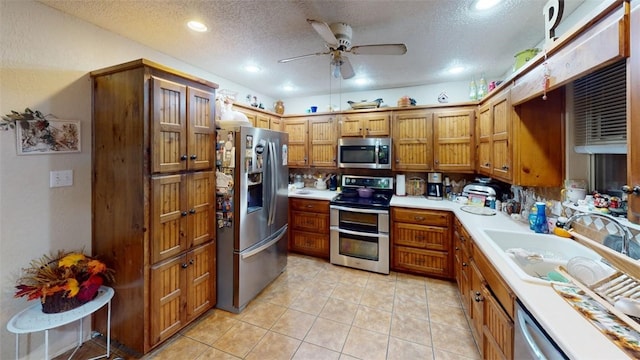 kitchen featuring sink, ceiling fan, light tile patterned floors, a textured ceiling, and stainless steel appliances