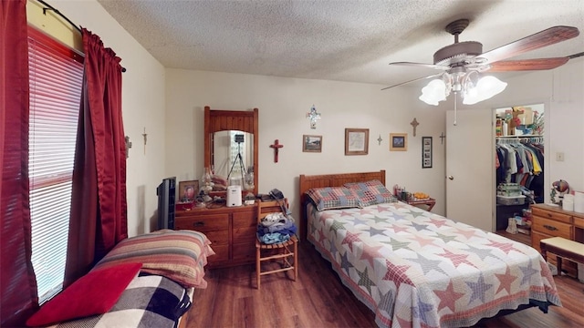 bedroom with ceiling fan, a closet, dark wood-type flooring, and a textured ceiling