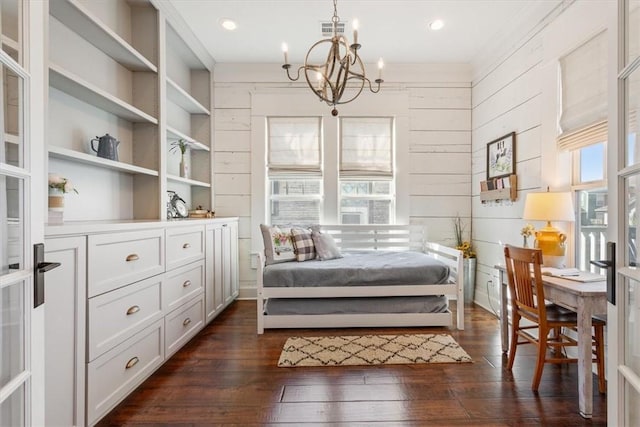 bedroom with wood walls, dark hardwood / wood-style flooring, and a chandelier