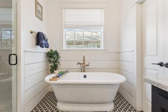 bathroom with wooden walls, vanity, plus walk in shower, and a wealth of natural light