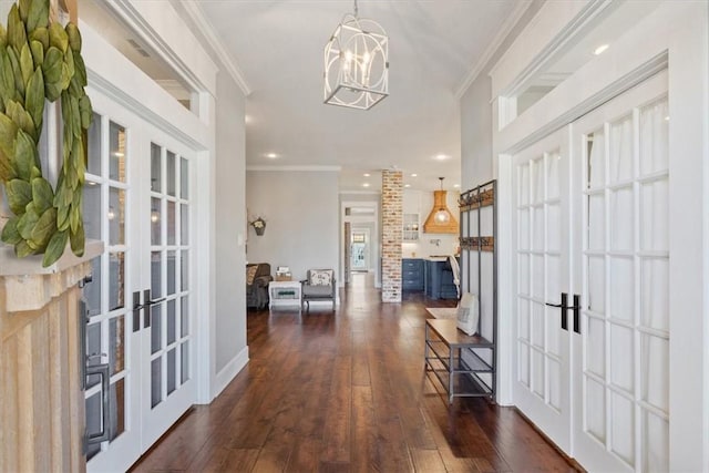 entryway with a chandelier, ornamental molding, dark wood-type flooring, and french doors