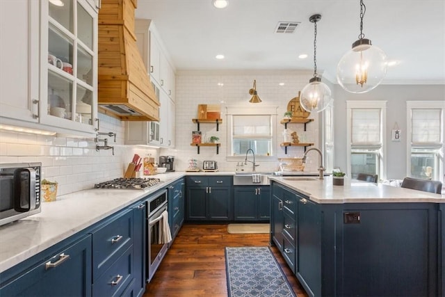 kitchen with blue cabinetry, dark wood-type flooring, backsplash, decorative light fixtures, and appliances with stainless steel finishes