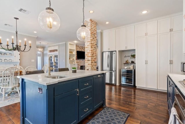 kitchen featuring sink, wine cooler, stainless steel fridge, pendant lighting, and a center island with sink