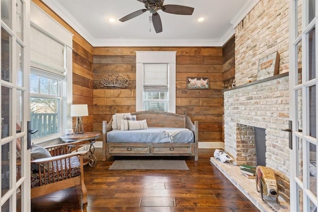 bedroom featuring ceiling fan, french doors, dark wood-type flooring, a fireplace, and ornamental molding