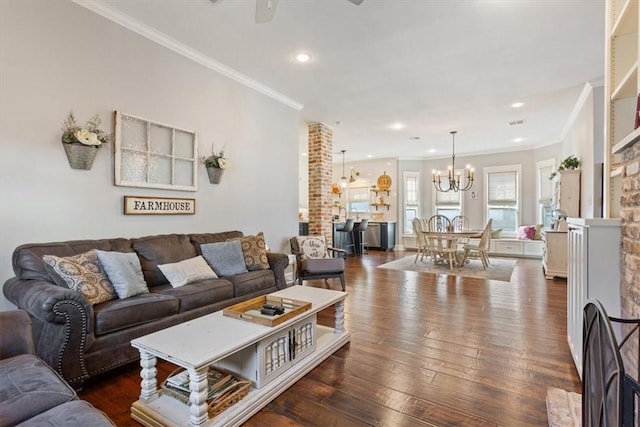 living room featuring a fireplace, crown molding, dark hardwood / wood-style flooring, and ceiling fan with notable chandelier