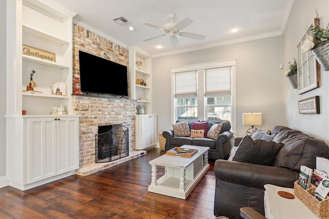 living room with dark wood-type flooring, a brick fireplace, ceiling fan, built in features, and ornamental molding