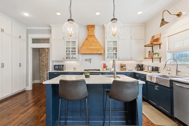 kitchen with white cabinetry, sink, an island with sink, custom exhaust hood, and appliances with stainless steel finishes