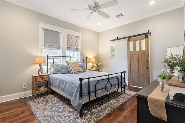 bedroom featuring a barn door, dark hardwood / wood-style floors, ceiling fan, and ornamental molding