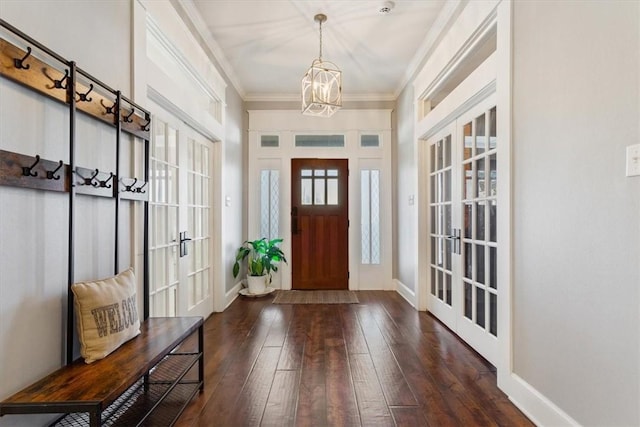 foyer entrance featuring french doors, dark hardwood / wood-style floors, ornamental molding, and a notable chandelier