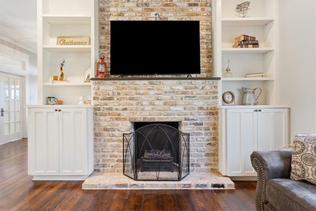 living room featuring a fireplace, built in features, and dark wood-type flooring