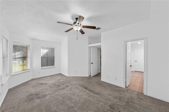 empty room featuring a textured ceiling, ceiling fan, and light carpet