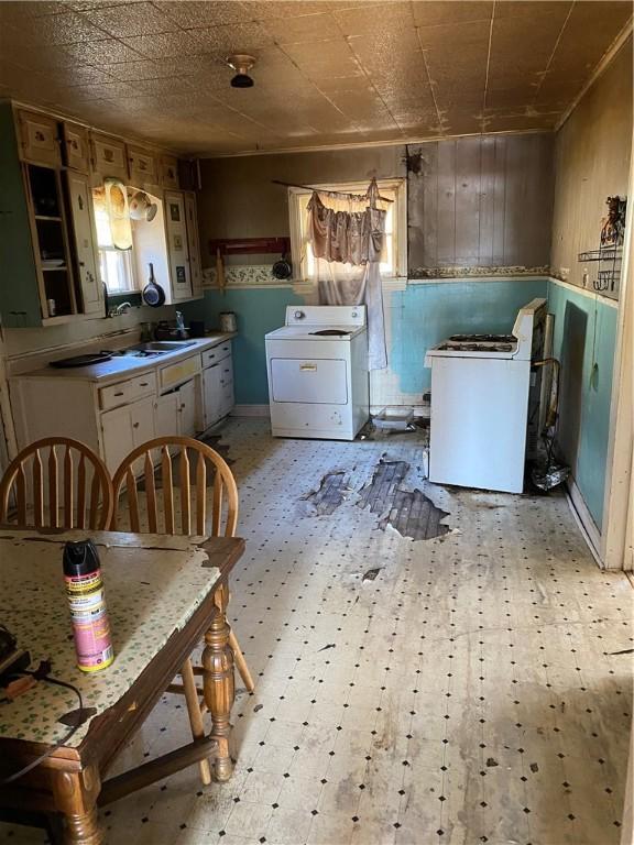 kitchen with wood walls, white cabinets, and washer / dryer