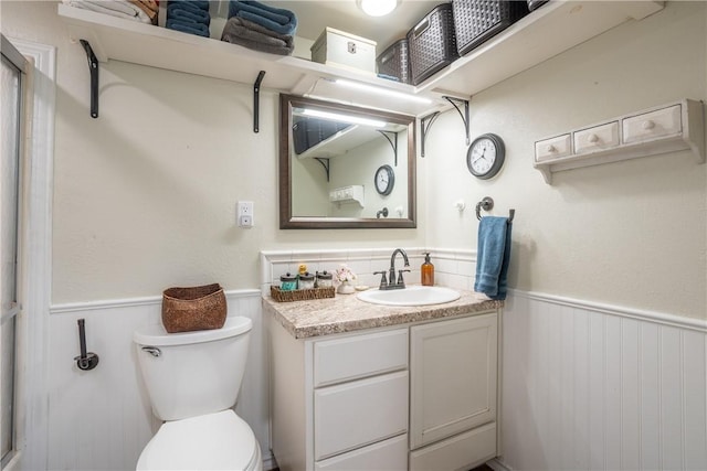 bathroom featuring a wainscoted wall, vanity, and toilet