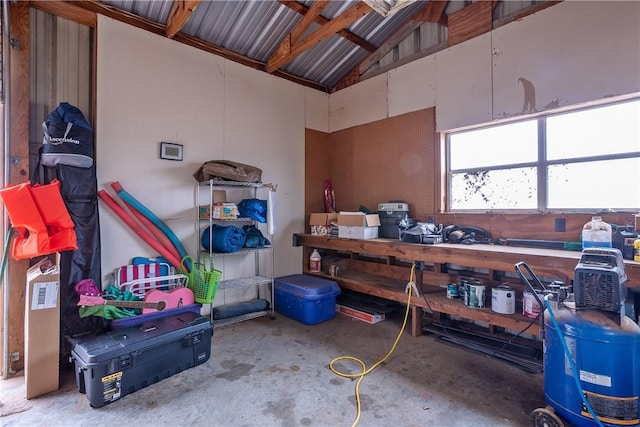 miscellaneous room with high vaulted ceiling, a workshop area, and unfinished concrete flooring