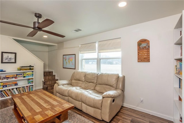 living room featuring dark wood-style flooring, visible vents, stairway, and baseboards