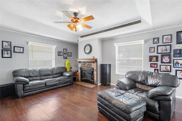 living room featuring a textured ceiling, a fireplace, ceiling fan, and dark wood-type flooring