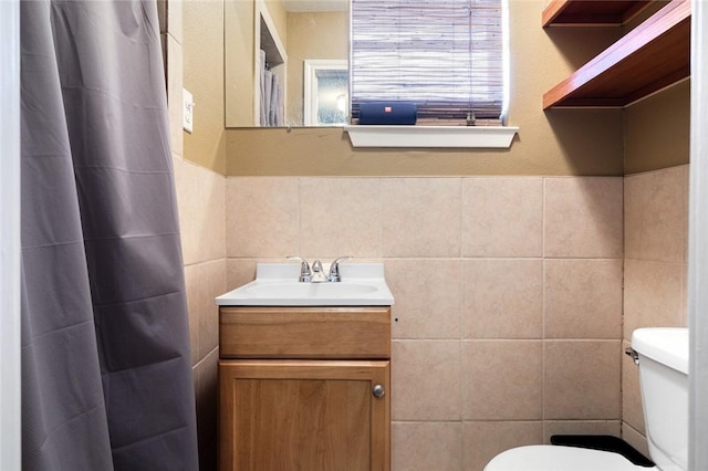 bathroom with vanity, tile walls, and toilet