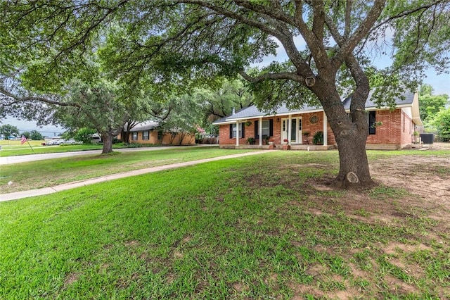 ranch-style home with covered porch, central air condition unit, and a front lawn