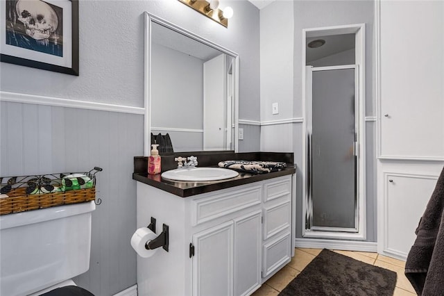 bathroom featuring tile patterned floors, vanity, toilet, and a shower with shower door