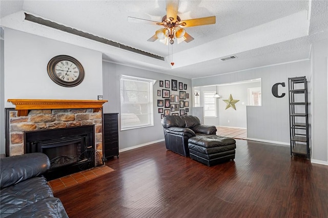 living room with a stone fireplace, dark hardwood / wood-style flooring, and a textured ceiling