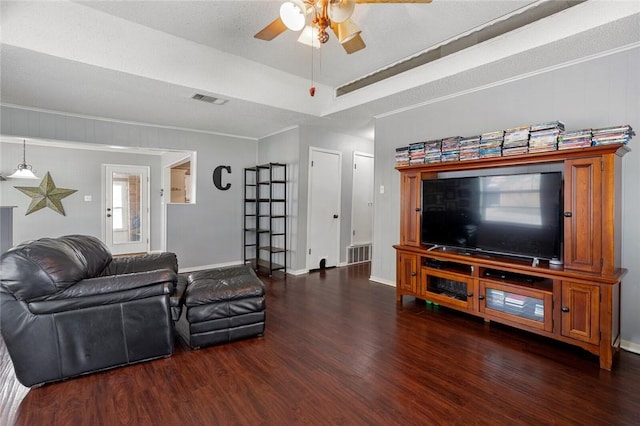 living room with dark hardwood / wood-style floors, ceiling fan, ornamental molding, and a textured ceiling