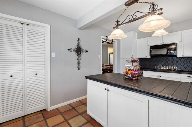 kitchen featuring beamed ceiling, decorative light fixtures, white cabinetry, and backsplash