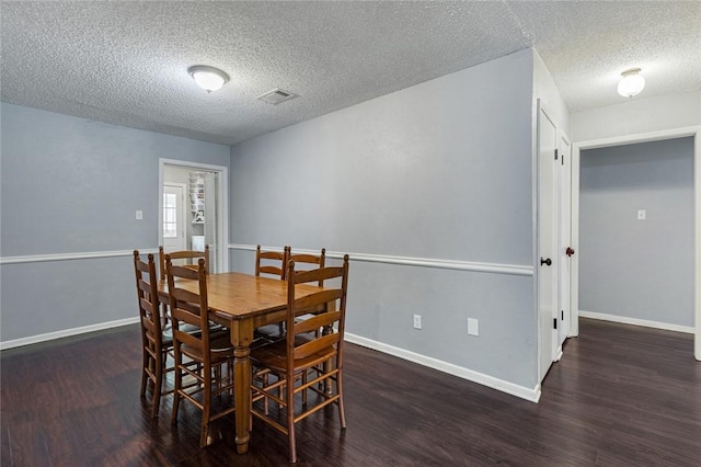 dining area with a textured ceiling and dark wood-type flooring