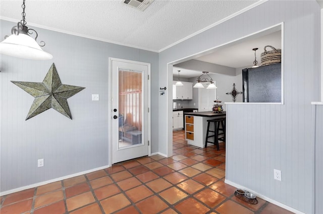 interior space featuring a textured ceiling, dark tile patterned floors, ornamental molding, and wood walls