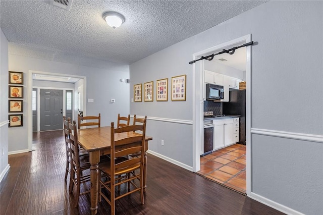 dining area with dark hardwood / wood-style floors and a textured ceiling