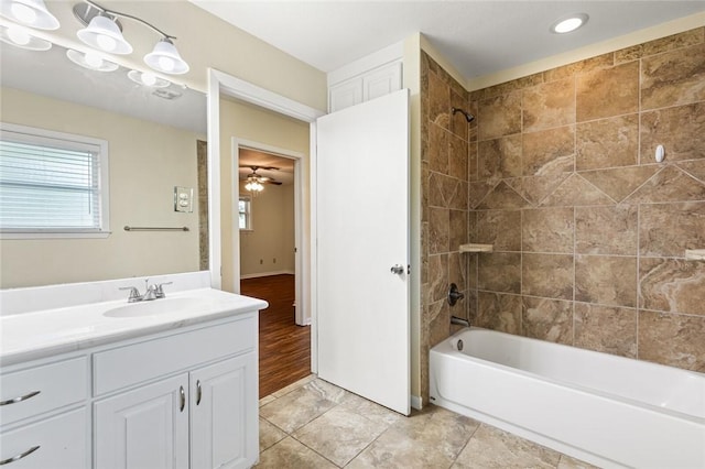 bathroom with ceiling fan, vanity, wood-type flooring, and tiled shower / bath combo