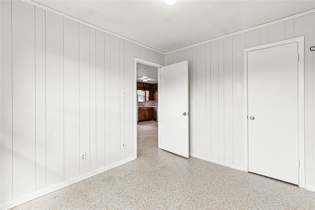 unfurnished bedroom with wood walls and a textured ceiling