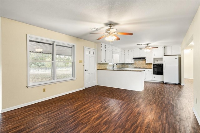 kitchen featuring kitchen peninsula, dark wood-type flooring, white refrigerator, white cabinetry, and black oven