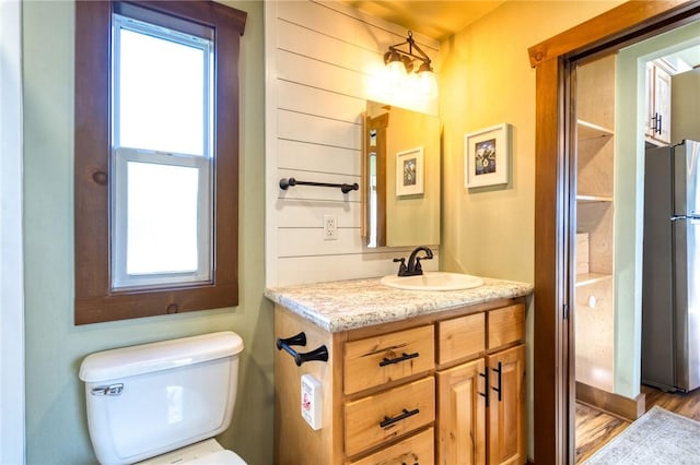 bathroom with hardwood / wood-style floors, vanity, toilet, and a healthy amount of sunlight