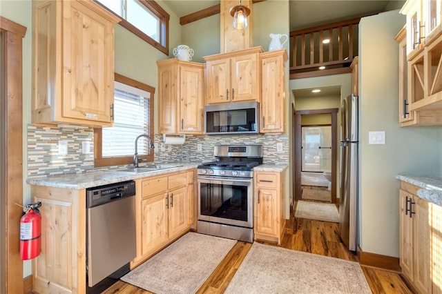 kitchen with light hardwood / wood-style floors, sink, appliances with stainless steel finishes, and tasteful backsplash