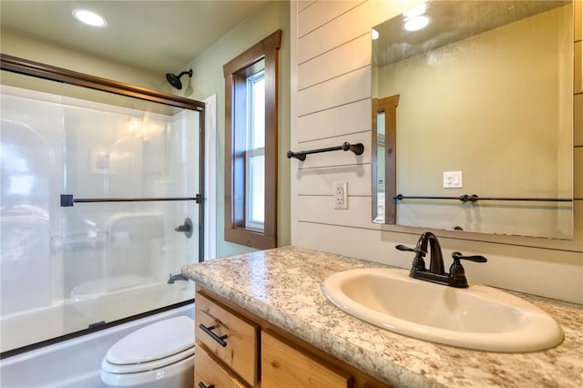 full bathroom featuring vanity, toilet, a healthy amount of sunlight, and bath / shower combo with glass door