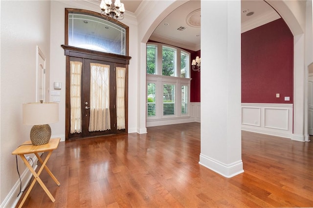 entrance foyer with hardwood / wood-style floors, a notable chandelier, a towering ceiling, and crown molding