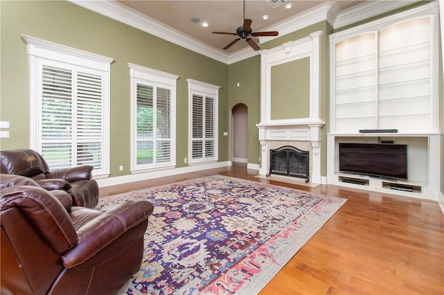 living room with crown molding, a large fireplace, ceiling fan, and hardwood / wood-style flooring