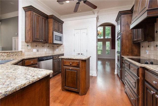 kitchen with light stone counters, crown molding, stainless steel appliances, and light hardwood / wood-style flooring