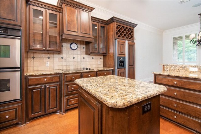 kitchen with a center island, black electric stovetop, light hardwood / wood-style flooring, decorative light fixtures, and stainless steel double oven