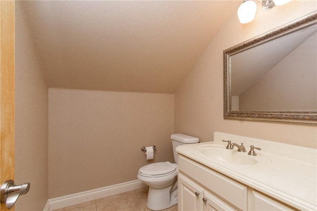 bathroom with toilet, vanity, tile patterned flooring, and vaulted ceiling