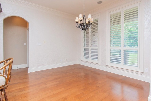 empty room with a chandelier, hardwood / wood-style flooring, and ornamental molding