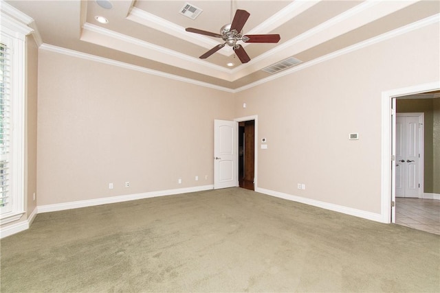 carpeted spare room featuring a raised ceiling, a wealth of natural light, ceiling fan, and ornamental molding