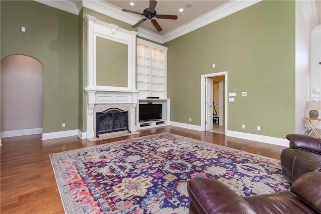 living room featuring ceiling fan, ornamental molding, a high ceiling, and hardwood / wood-style flooring