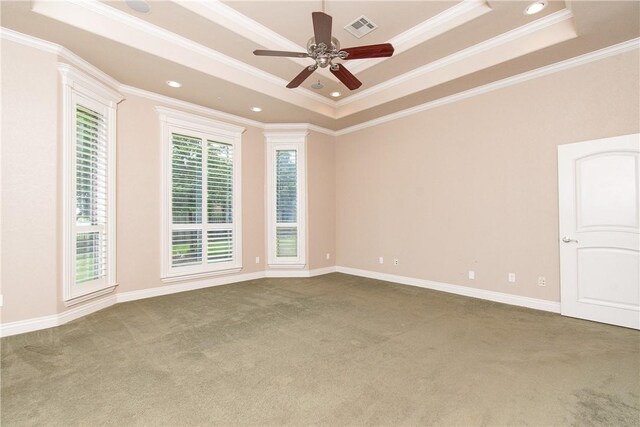 carpeted empty room with a raised ceiling, ceiling fan, and ornamental molding