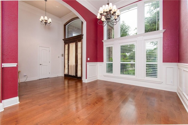 foyer entrance featuring a chandelier, wood-type flooring, a towering ceiling, and crown molding