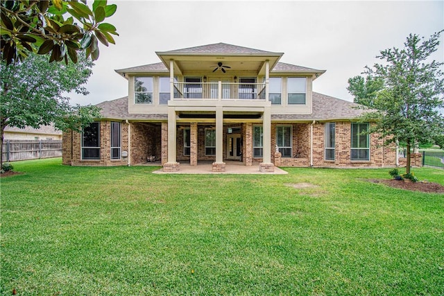 back of property with a yard, ceiling fan, a balcony, and a patio