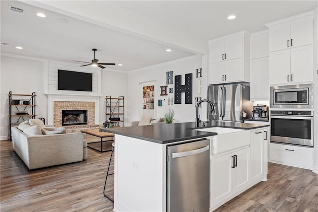 kitchen featuring stainless steel appliances, dark countertops, open floor plan, and crown molding