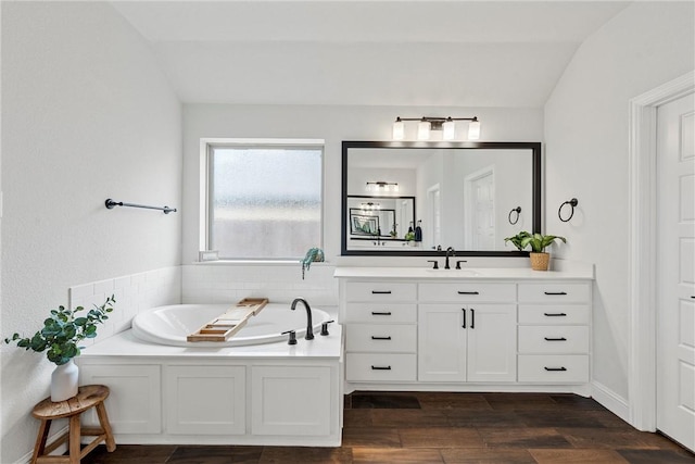 full bathroom with a garden tub, vaulted ceiling, vanity, and wood finished floors