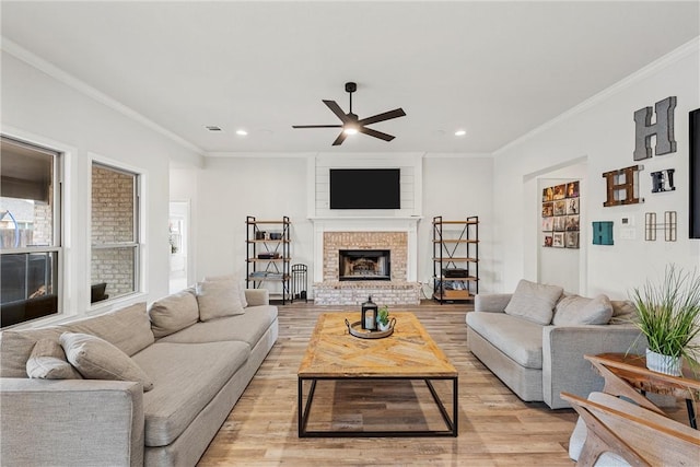 living area featuring recessed lighting, a brick fireplace, crown molding, and light wood-style flooring